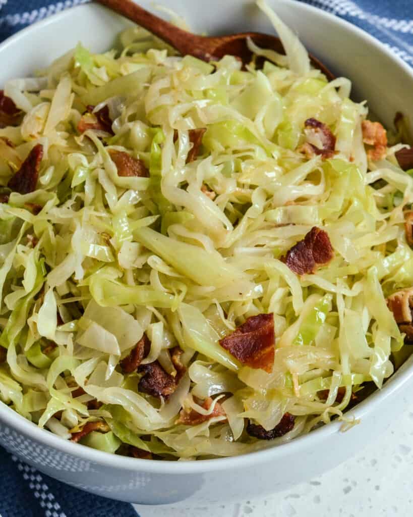 A bowl full of fried cabbage with bacon and onions. 