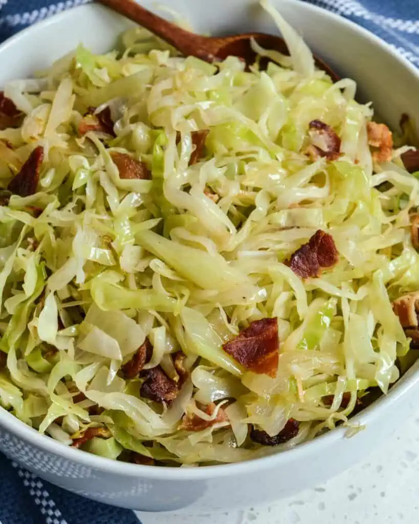 A bowl full of fried cabbage with bacon and onions. 