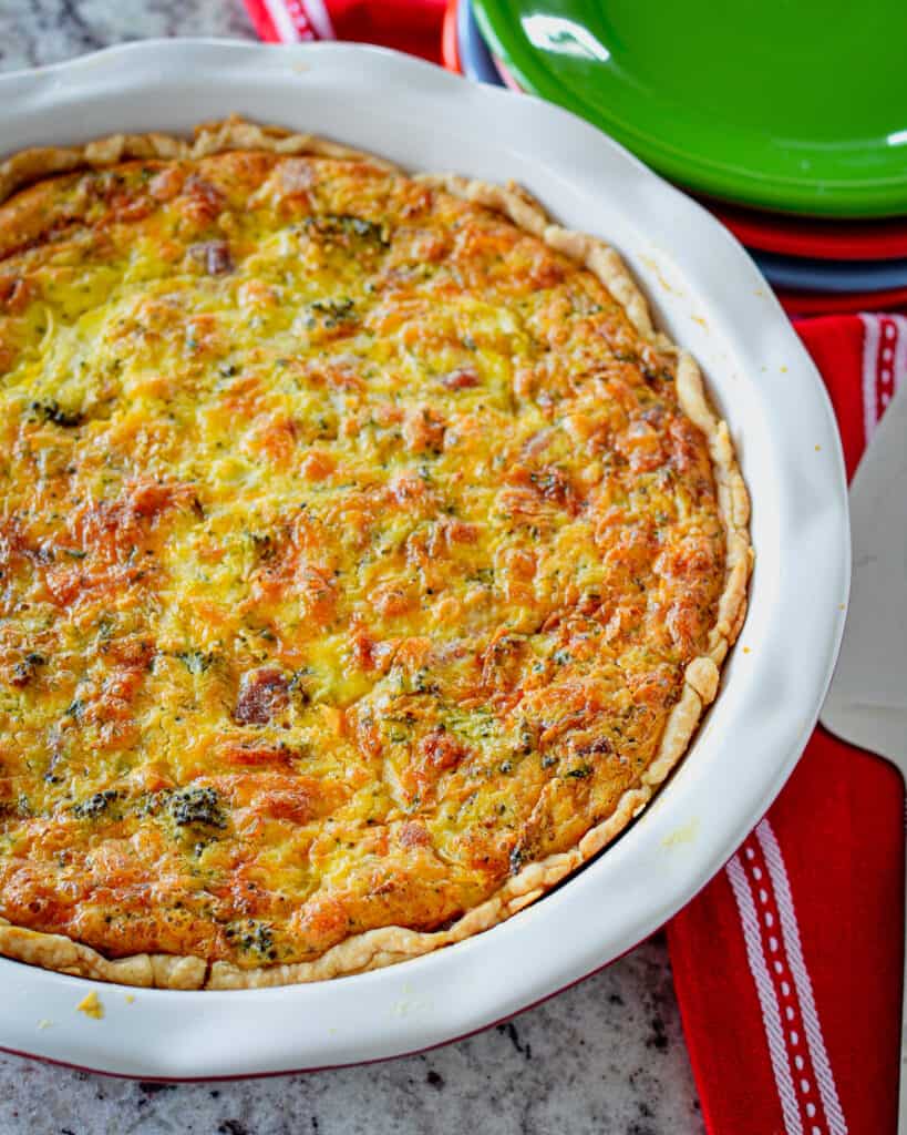 An overhead view of ham and ceese quiche with a red and white towel on the side.