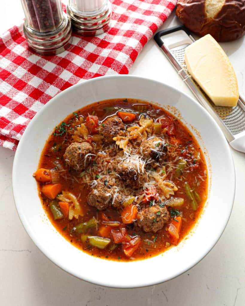 An overhead view of meatball soup with a sprinkle of Parmesan cheese. 