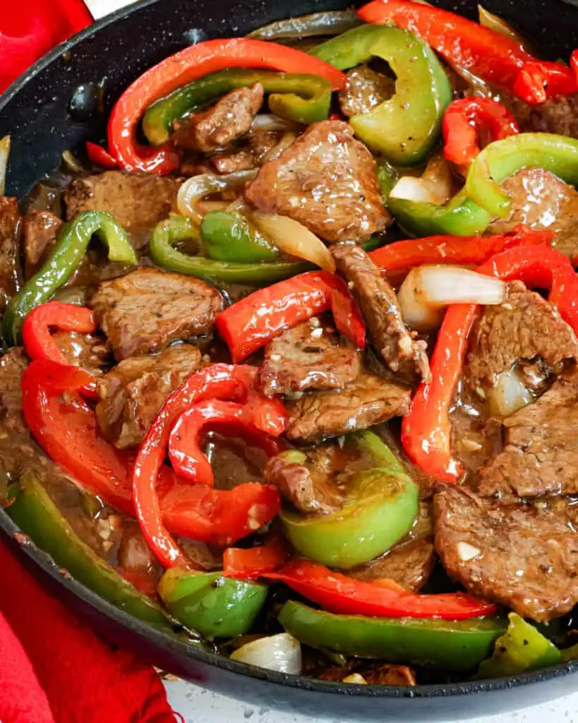 A favorite one skillet pepper steak with stir-fried crisp-tender steak, green and red bell peppers, and sweet yellow onion in a sweet and savory beef ginger sauce.