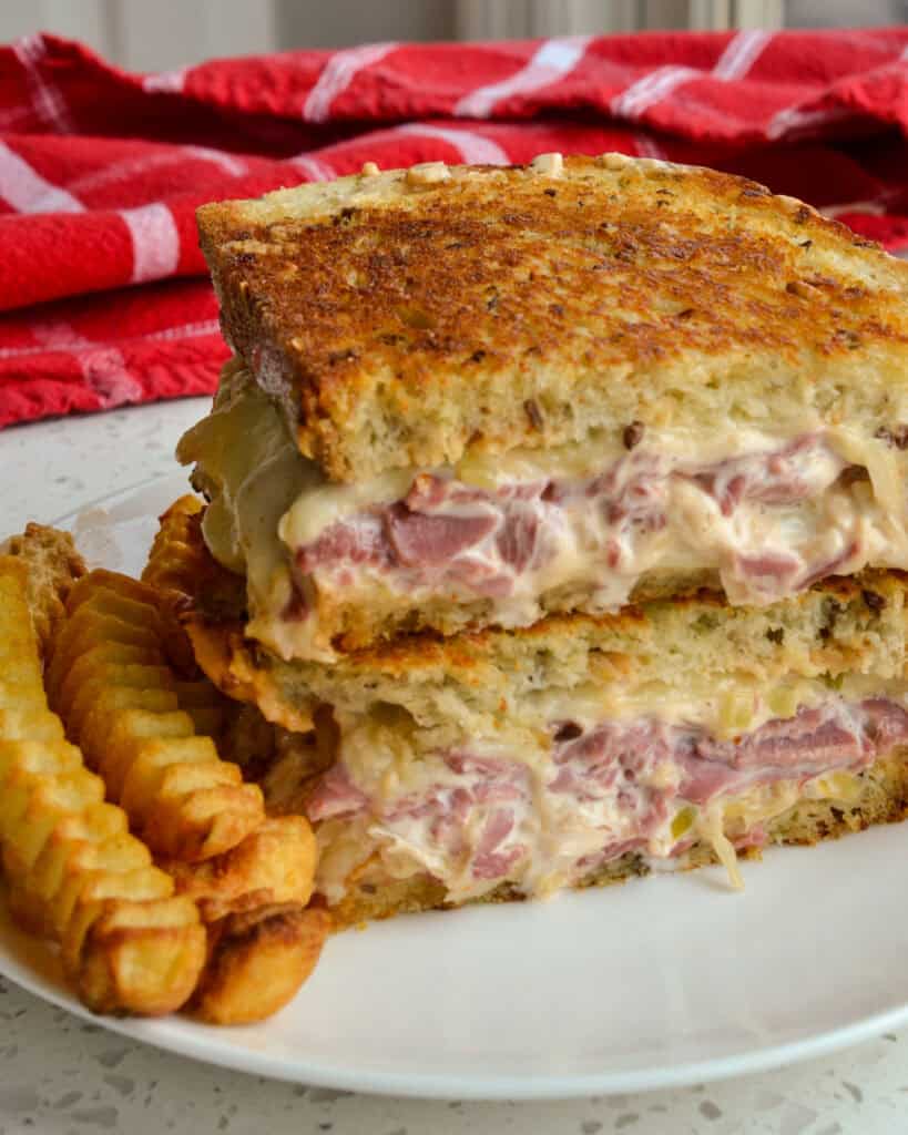 Reuben Sandwich is piled high with melty Swiss cheese, thin layers of sliced corned beef, sauerkraut, and homemade thousand island dressing, all on rye bread.