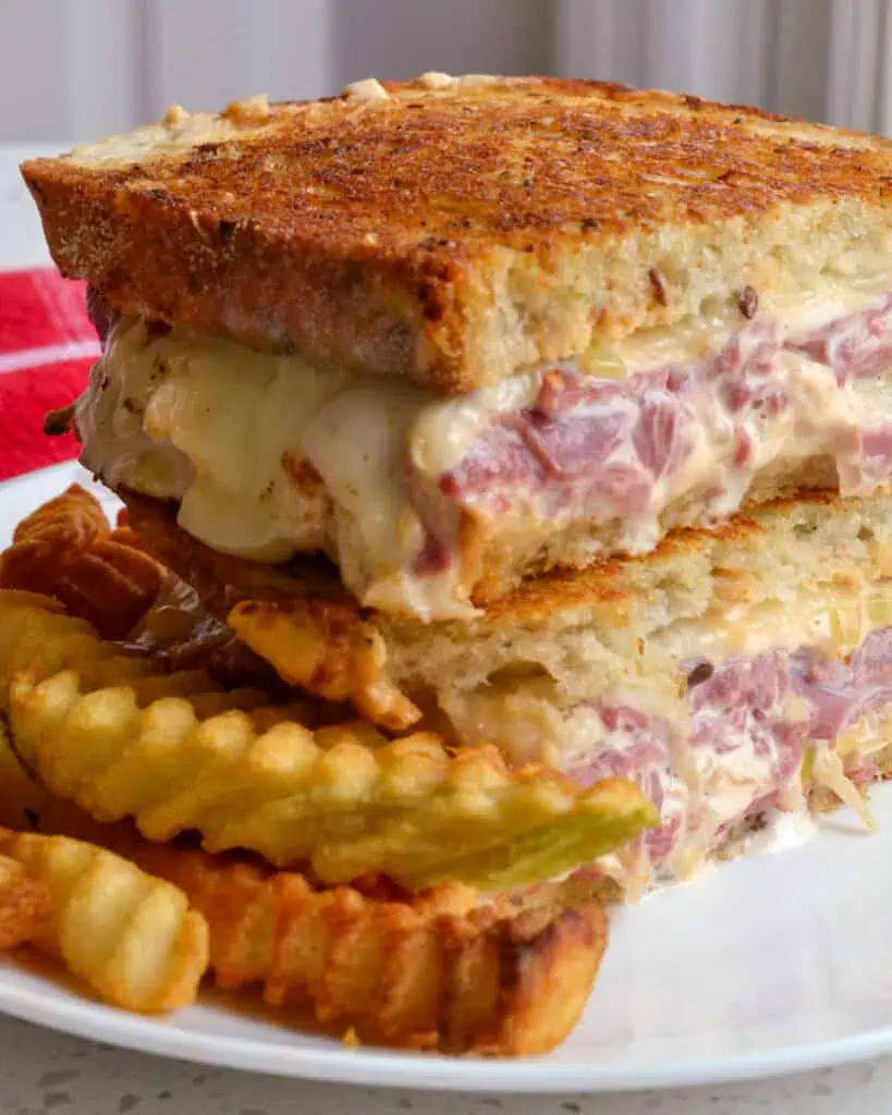 This scrumptious toasted Reuben Sandwich is piled high with melty Swiss cheese, thin layers of sliced corned beef, sauerkraut, and homemade thousand island dressing, all on rye bread.