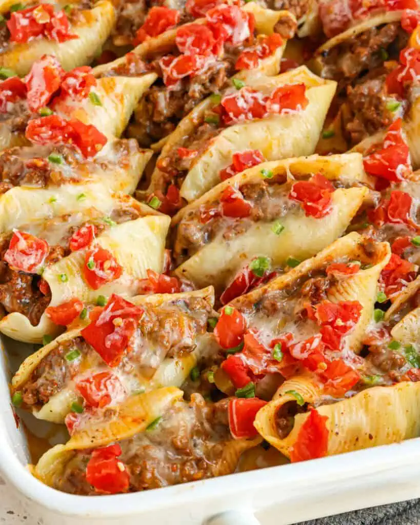 Taco Stuffed Shells are jumbo pasta shells plump full of seasoned ground beef, onions, salsa, cheddar, and Monterey Jack Cheese.  