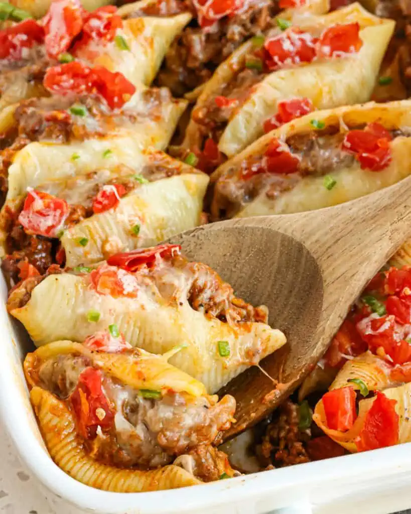 These delicious Taco Stuffed Shells are jumbo pasta shells stuffed with seasoned ground beef, onions, salsa, cheddar, and Monterey Jack Cheese.  Bake up a batch tonight and get ready to hear the praises.  