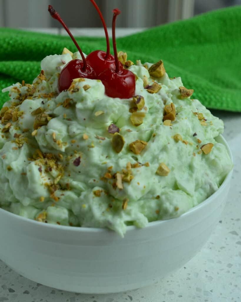 This classic Watergate Salad Recipe, also known as Pistachio Delight and Green Fluff, is a fresh blast from the past with the flavors of crushed pineapple, pistachio pudding, pistachio nuts, mini marshmallows, and fresh whipped cream.  