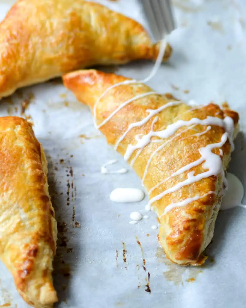 Fresh baked apple turnovers drizzled with glaze. 