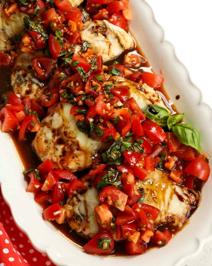 Chicken bruschetta with tomatoes, frush basil, and melted mozzarella on a serving platter. 