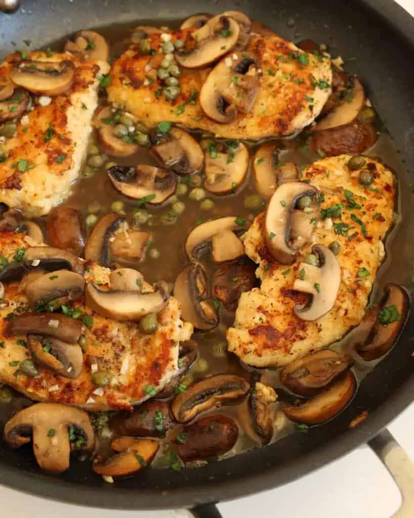 Return the chicken to the skillet and spoon the sauce, mushrooms, and capers over the chicken.