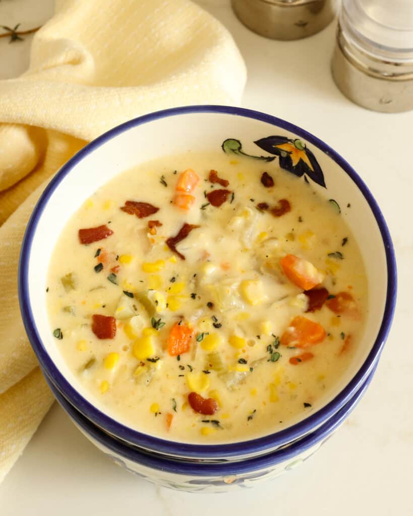 Two stacked bowls with the top one being filled with corn chowder. 