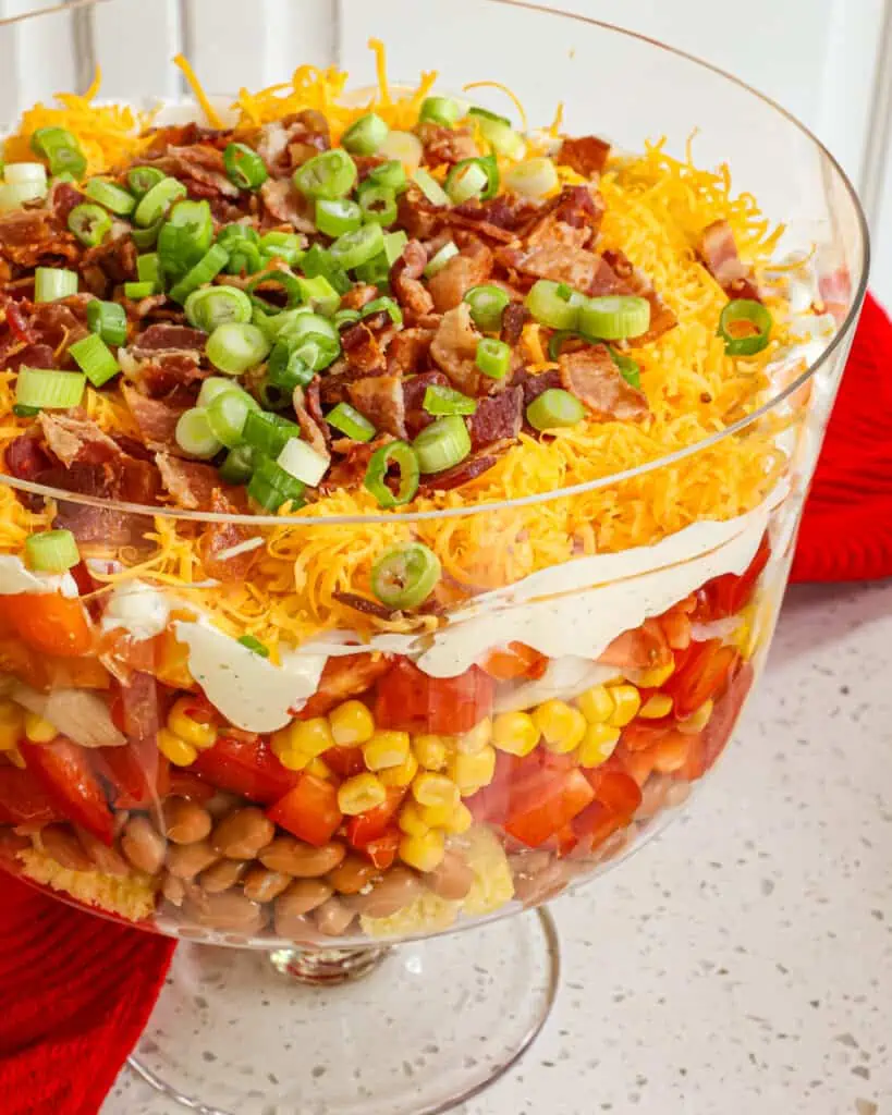 Layered Southern cornbread salad with bell pepper, tomatoes, bacon, cheddar, and ranch dressing. 