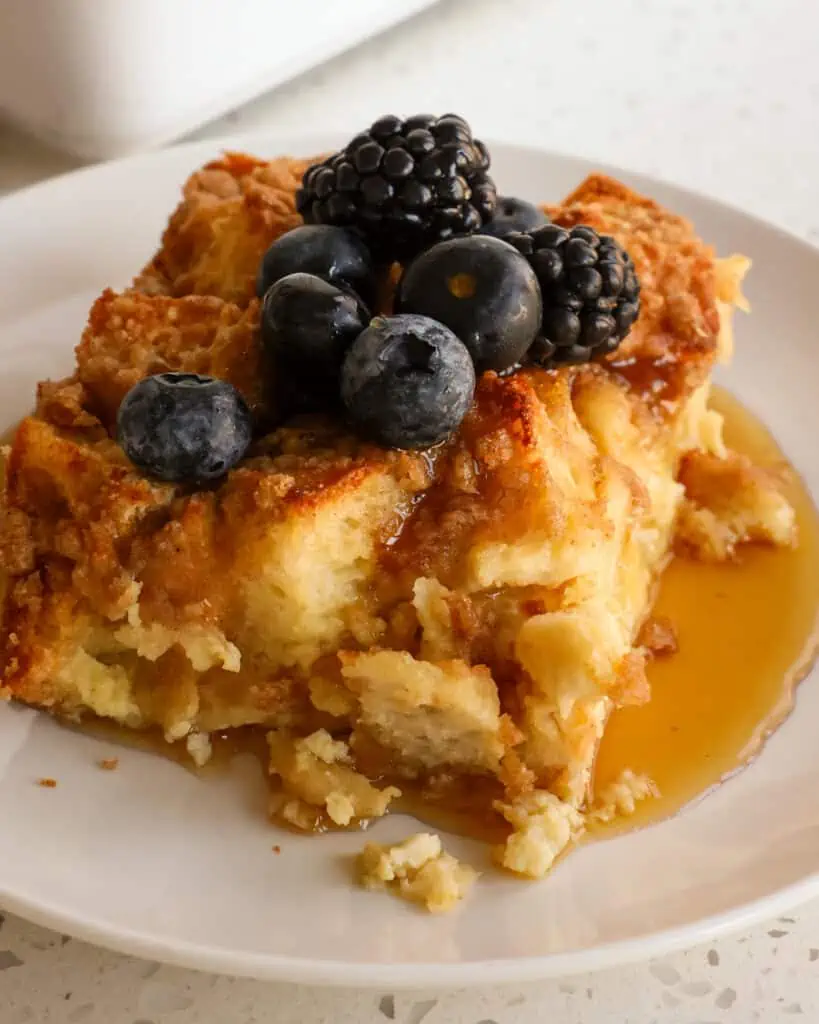 A slice of overnight French toast casserole with blueberries and syrup.