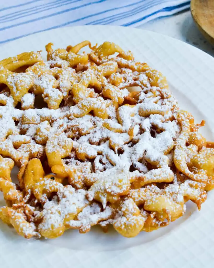 These fun and easy Funnel Cakes are crispy, hot, and delicious!  Better than any fair cakes, these are made right in the confines of your own kitchen in less than twenty minutes.