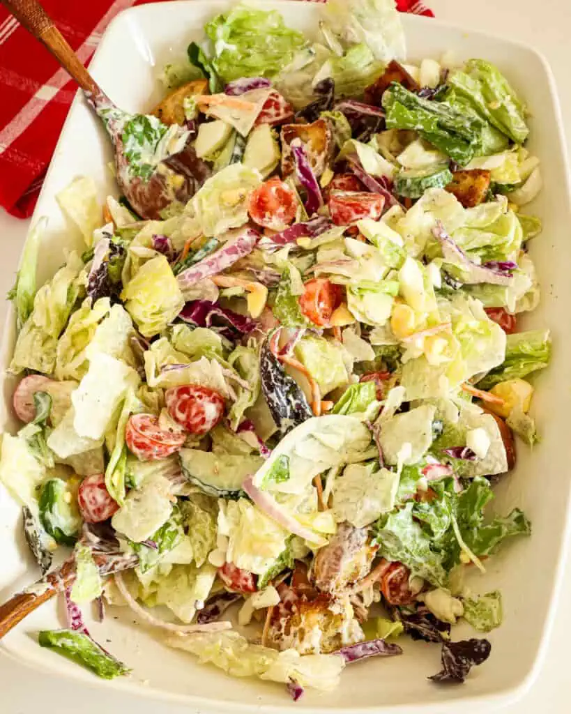 This easy garden salad combines iceberg lettuce with fresh vegetables like tomatoes, cucumbers, red onions, and radishes, all drizzled with a homemade buttermilk dressing and topped with chopped hard-boiled eggs and homemade croutons.
