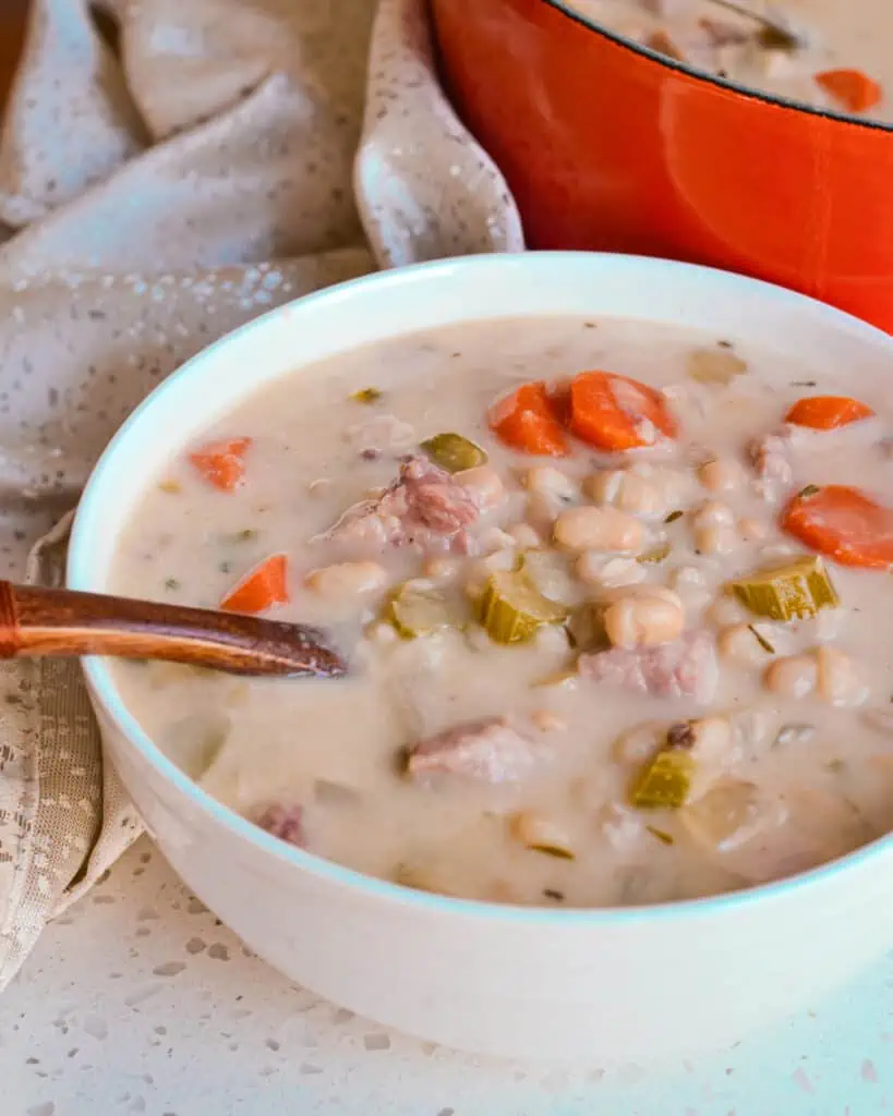 A close up view of a bowl full of ham and bean soup. 