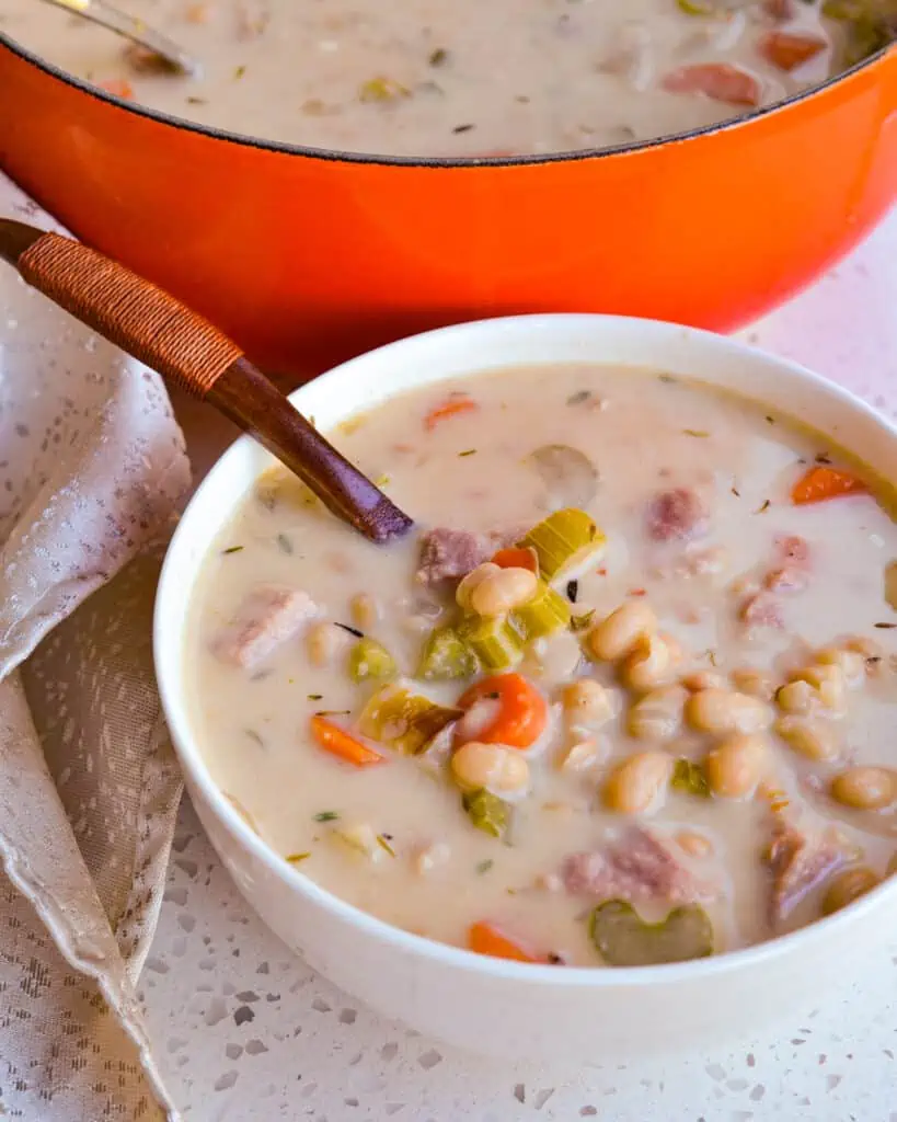 A single serving bowl full of ham and bean soup. 