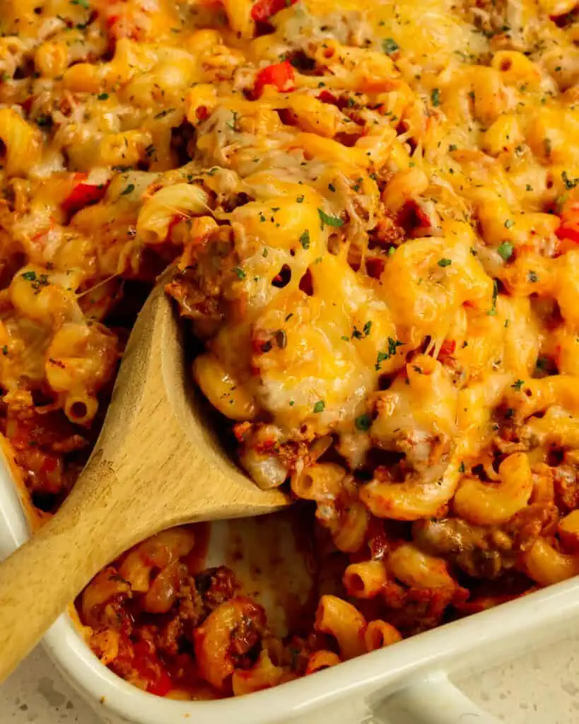 A large wooden spoon full of cheesy hamburger casserole 