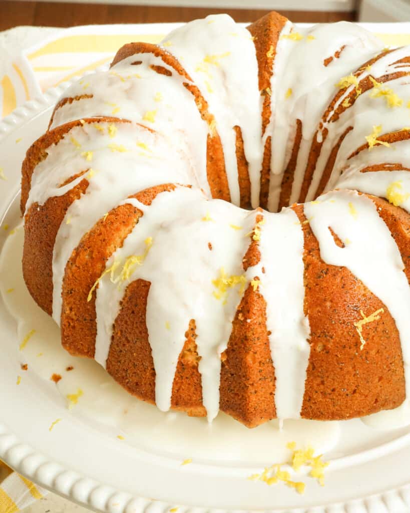 A made from scratch Lemon Poppy Seed Cake with a two ingredient lemon glaze on a white cake stand.