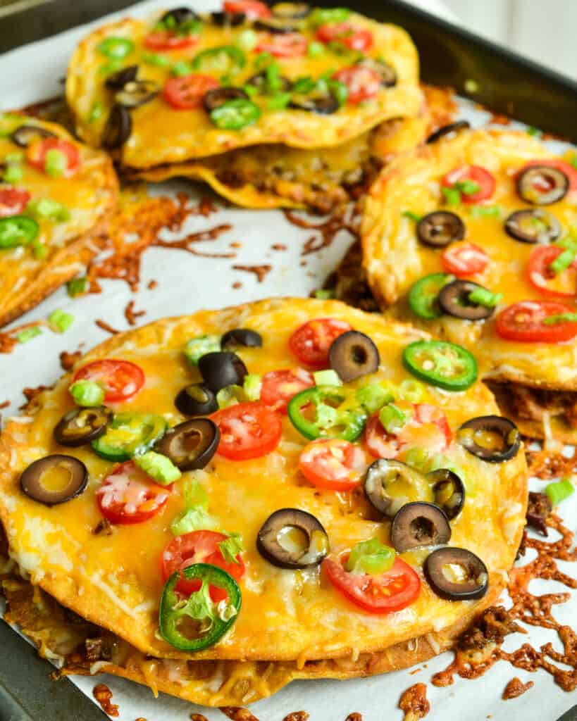 Mexican Pizzas stuffed with refried beans and taco seasoned ground beef then topped with oodles of cheese and tomatoes.