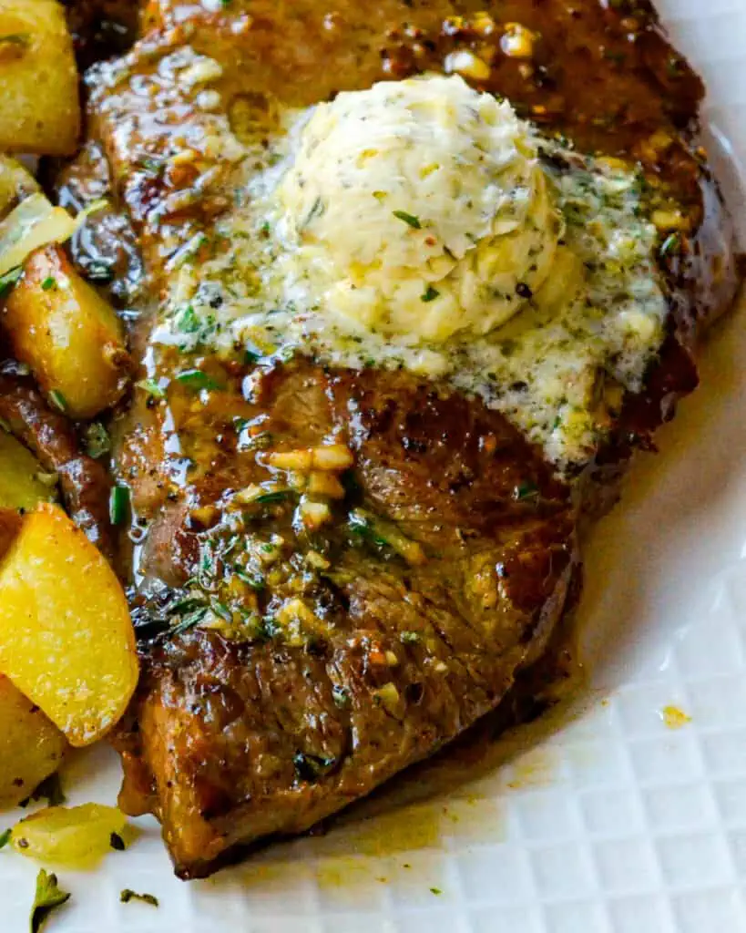 Juicy and tasty New York Strip Steaks seared in a cast iron skillet and braised with a quick and easy garlic herb butter.  