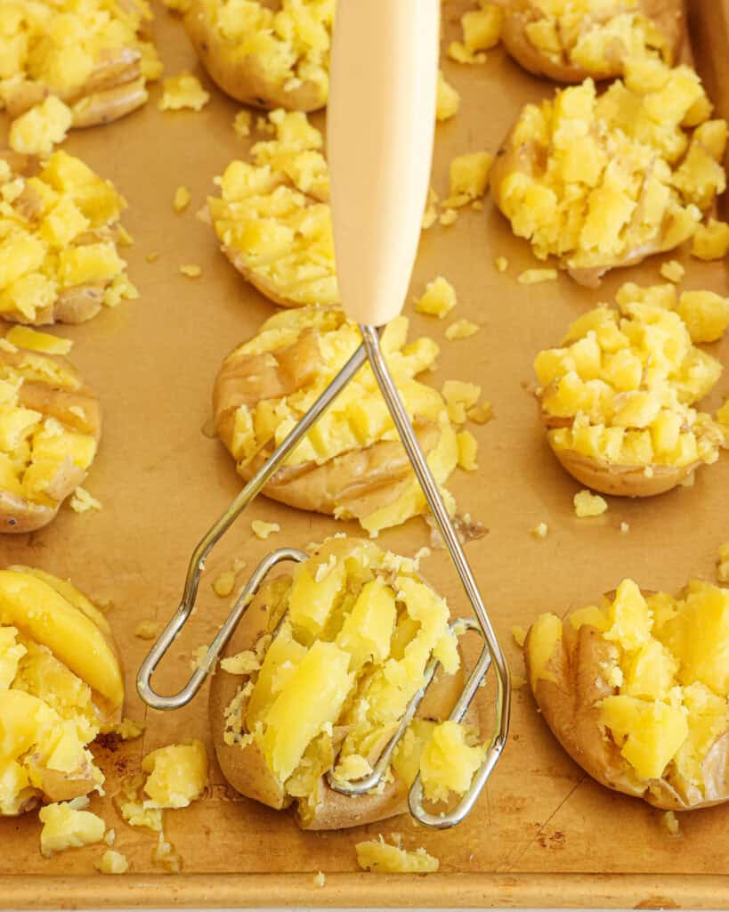 Using a potato masher, smash the potatoes, trying to keep them in one piece. Brush the potatoes with the remaining olive oil mixture.