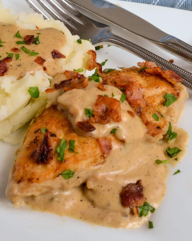 Smothered Chicken on a single serving plate with mashed potatoes and gravy. 