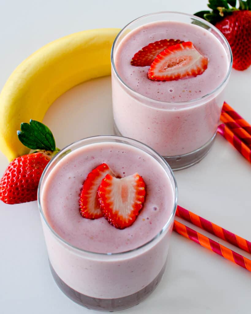 Overhead view of two short glasses full of strawberry banana smoothie, 