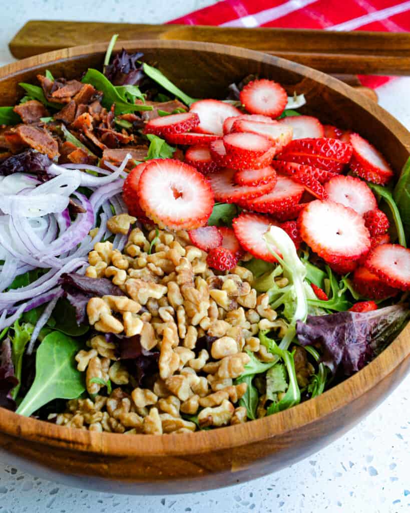 This delicious spring and summer salad combines fresh strawberries, crisp smoked bacon, sweet red onions, salty feta cheese, and crunchy walnuts with an easy-to-make six-ingredient creamy poppy seed dressing. 