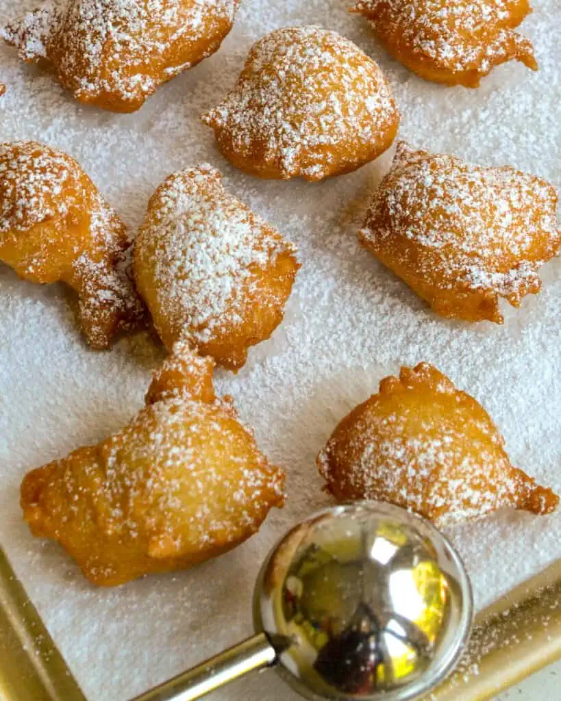 Zeppole on paper towels sprinkled with powdered sugar. 