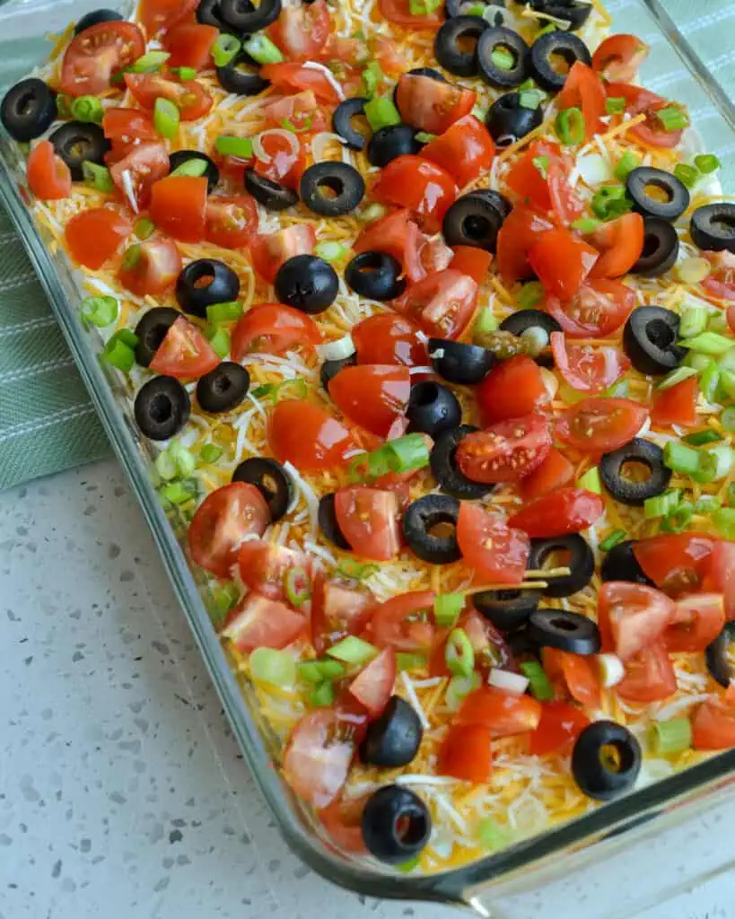 This Tex Mex dip is layered with beans, avocado, sour cream, and cheese. 