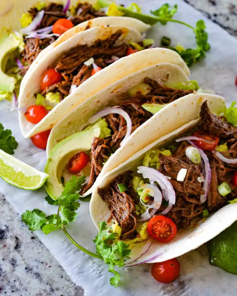 Barbacoa Tacos are filled with tender chuck roast slow-cooked in a spicy, flavor-packed sauce that comes together quickly in a food processor.