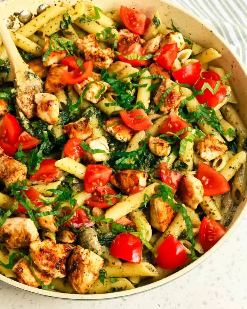 Quick and easy Chicken Pesto Pasta combines golden brown chicken pieces with fresh sauteed mushrooms and spinach, tomatoes, and penne pasta all tossed in pesto sauce.