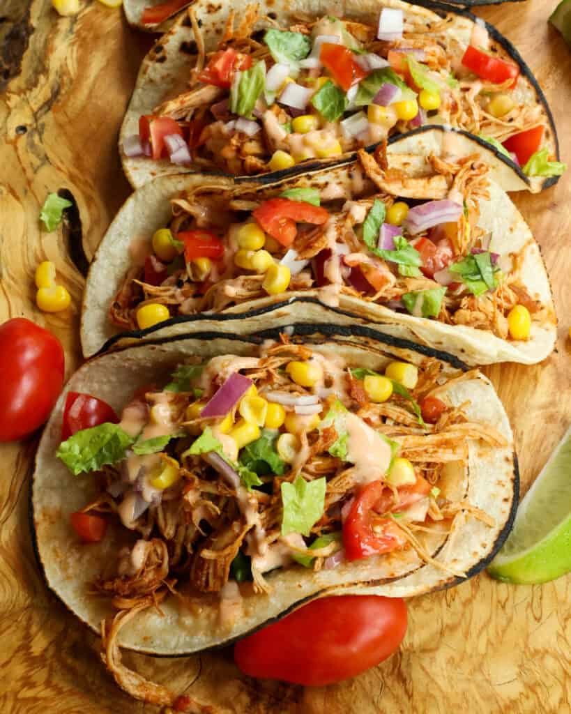 Lightly charred corn tortillas with slow cooked chicken, lettuce, tomatoes, and corn. 