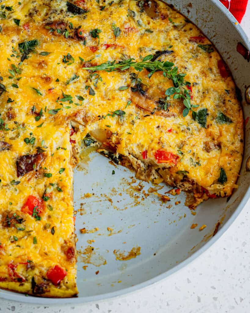 A classic egg frittata is an open-faced omelet made with various vegetables, seasonings, herbs, sometimes bacon, sausage, or ham, and shredded cheese like cheddar and Monterey Jack Cheese.