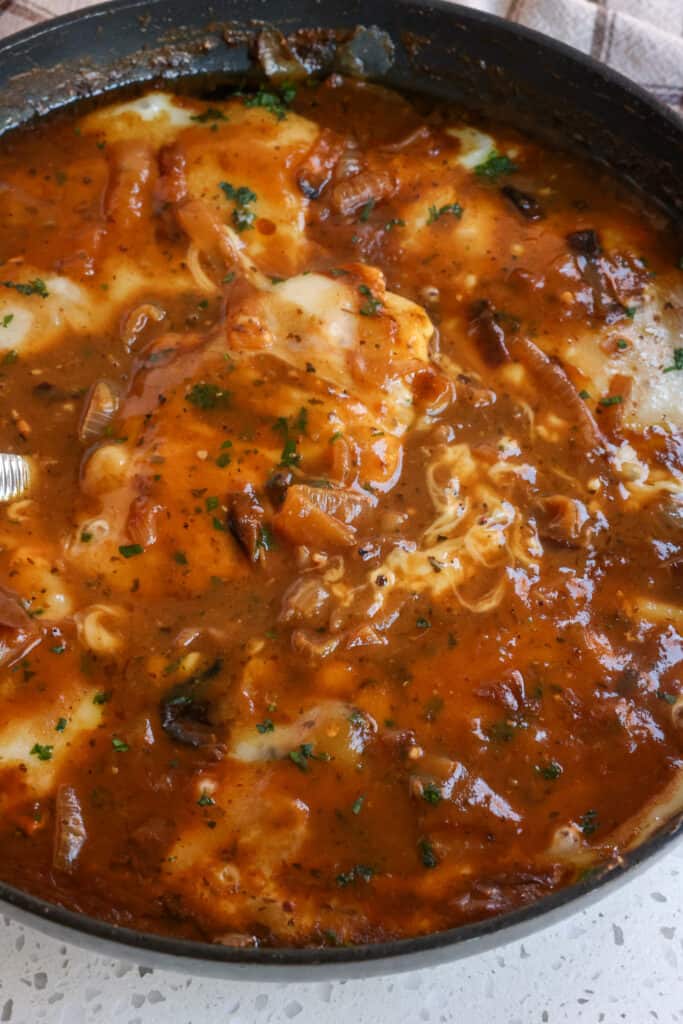 French Onion Chicken is pan-seared chicken cutlets smothered in a rich French Onion gravy and topped with Parmesan Cheese, Swiss Cheese, and fresh parsley.