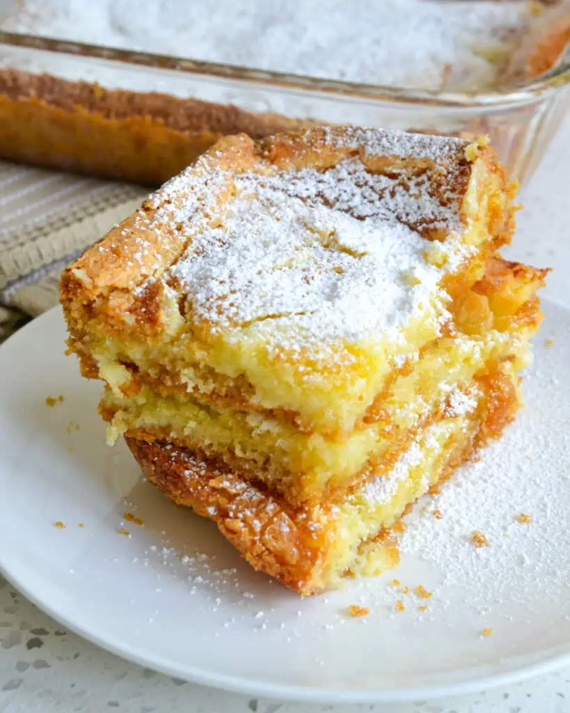 Three pieces of gooey butter stacked on a plate. 