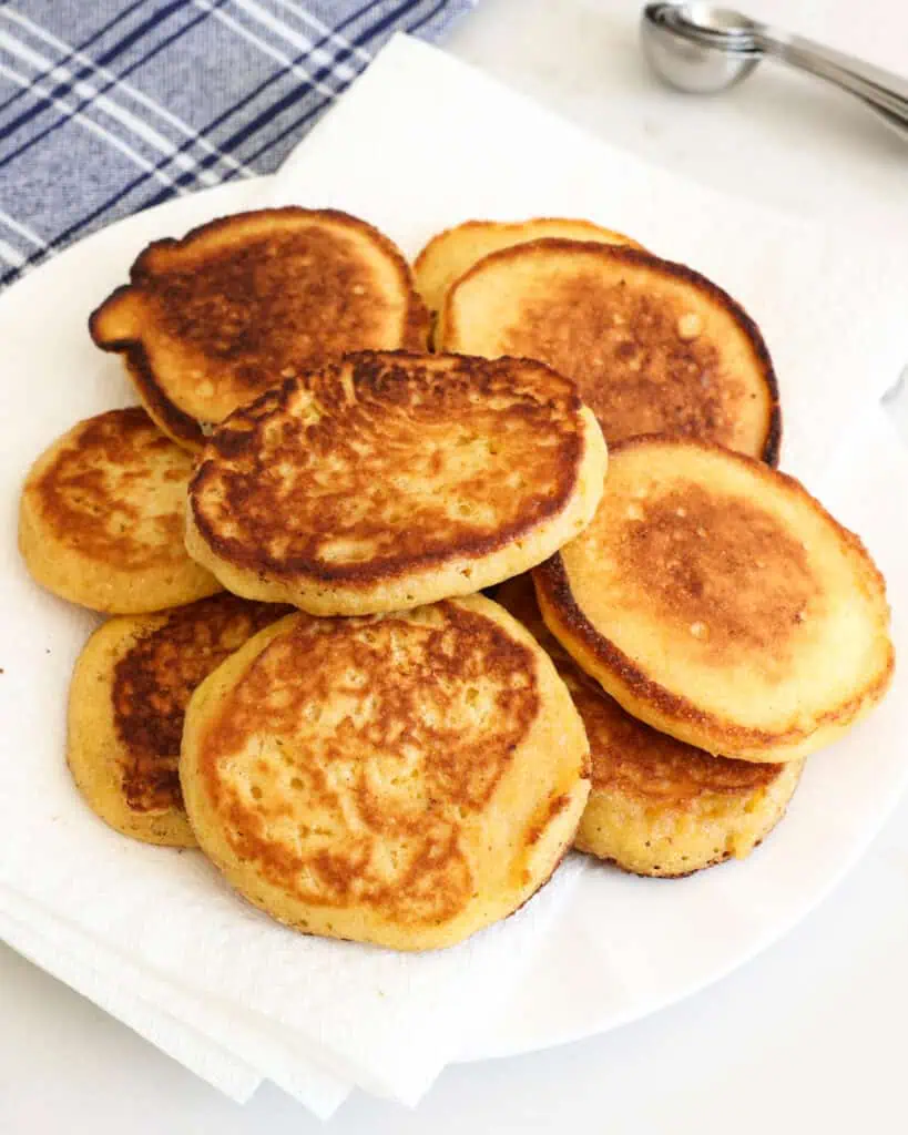 A pile of john cakes on a paper towel lined plate. 