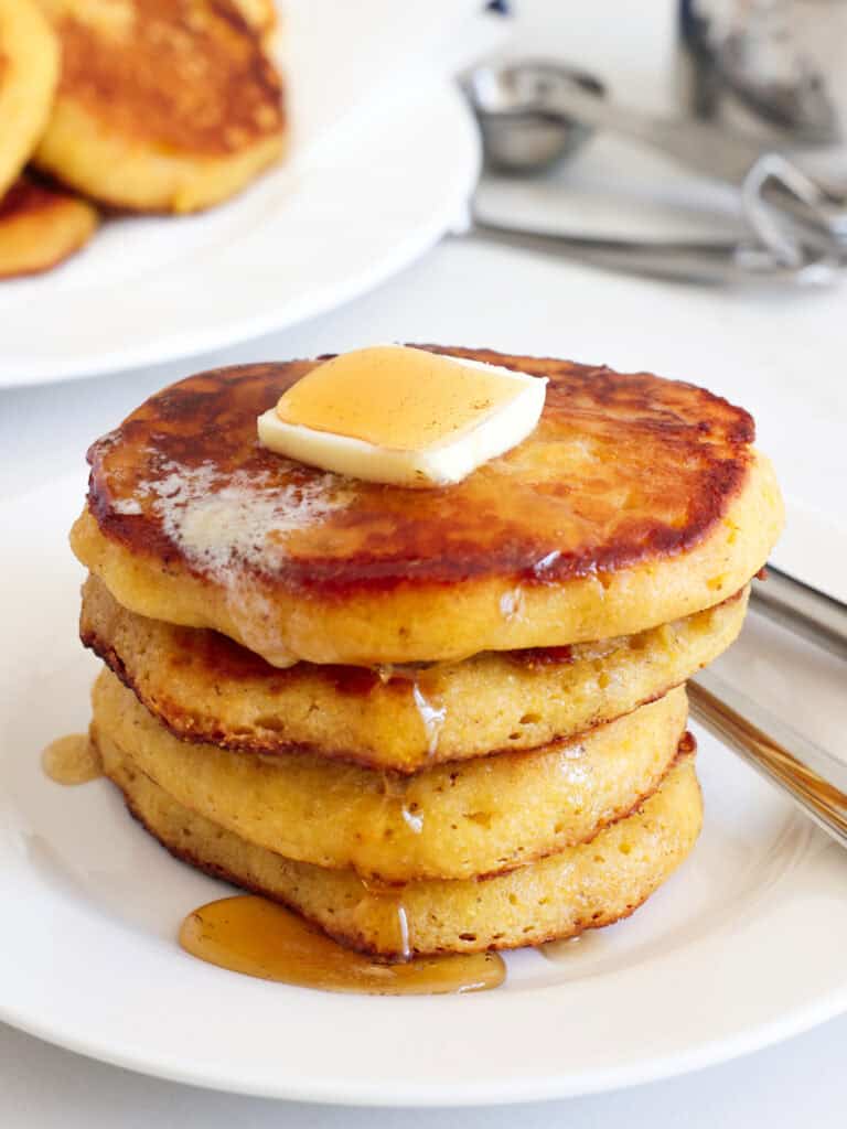 Johnny cakes with butter and maple syrup on a plate. 