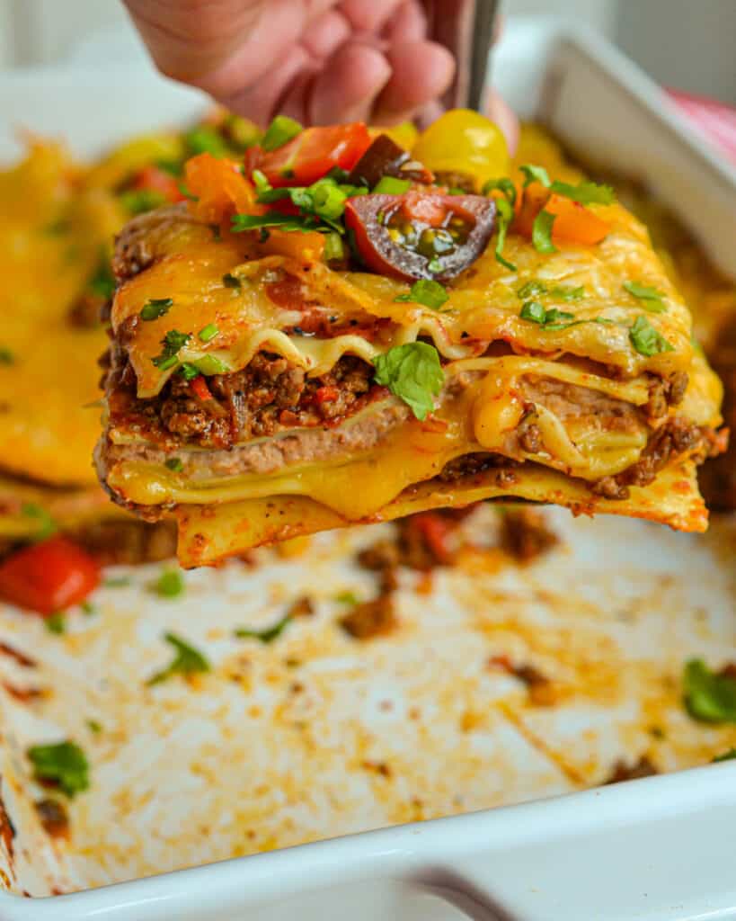 This Mexican Lasagna has layers of melted cheese, taco seasoned  ground beef, and creamy refried beans. 