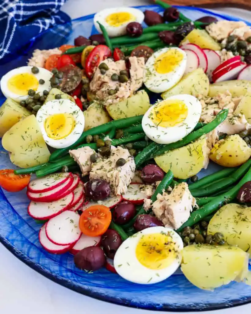 A salad of fresh vegetables, red potatoes, eggs, olives and tuna drizzled with a tangy light mustard vinaigrette.