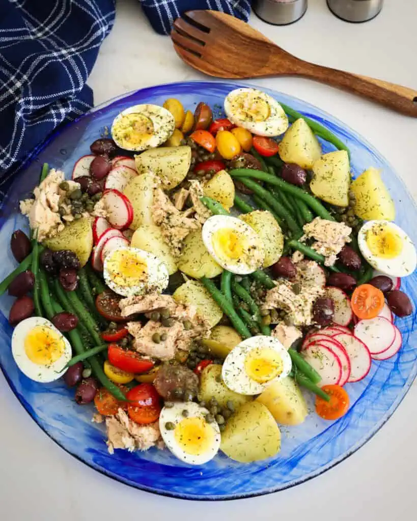 Nicoise Salad is a salad with vegetables, Nicoise olives, red potatoes, hard boiled eggs and tuna with mustard vinaigrette. 
