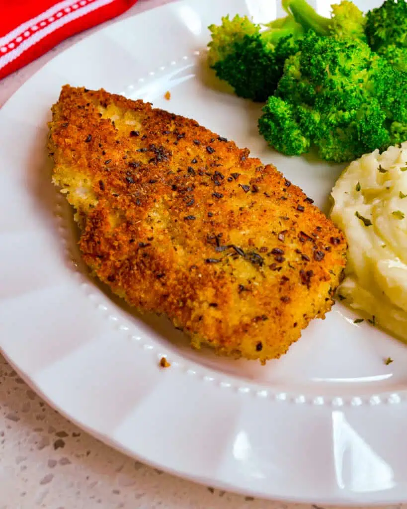 Crisp Parmesan Crusted Chicken on a dinner plate with mashed potatoes and broccoli. 