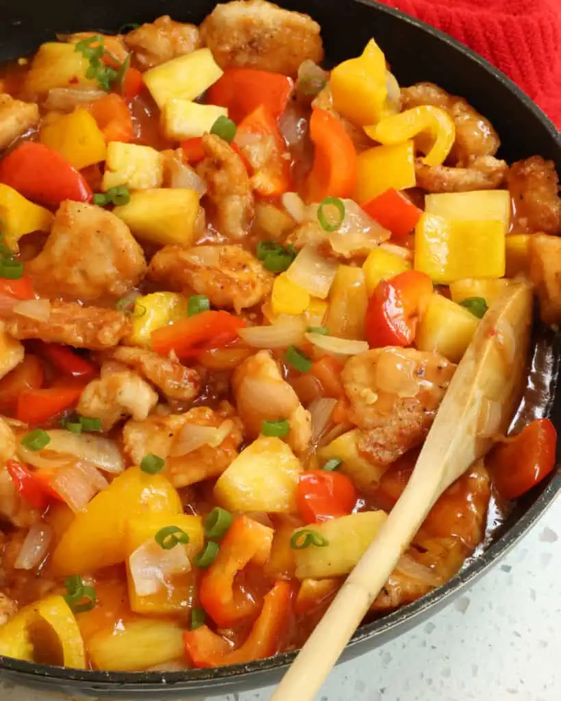 This tasty Pineapple Chicken combines crispy fried chicken pieces with pineapple, bell peppers, onions, garlic, and green onions in a sweet ginger pineapple sauce.