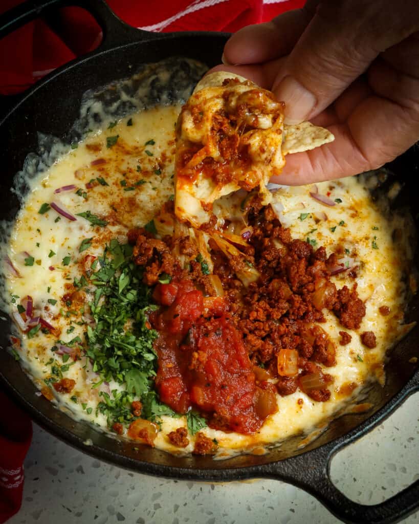 Queso Fundido is a dip with creamy melted cheese, chorizo, spices and toppings served with tortilla chips or tortillas. 