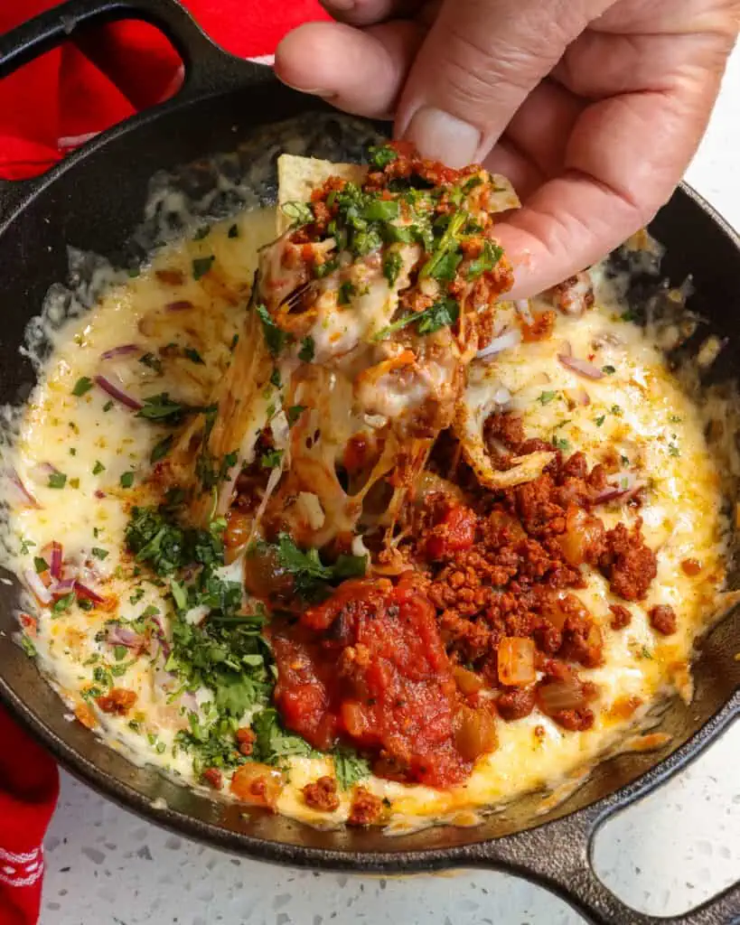 Queso Fundido is layered with melted cheese, chorizo, sauteed onions and topped with diced tomatoes, and minced jalapenos. 