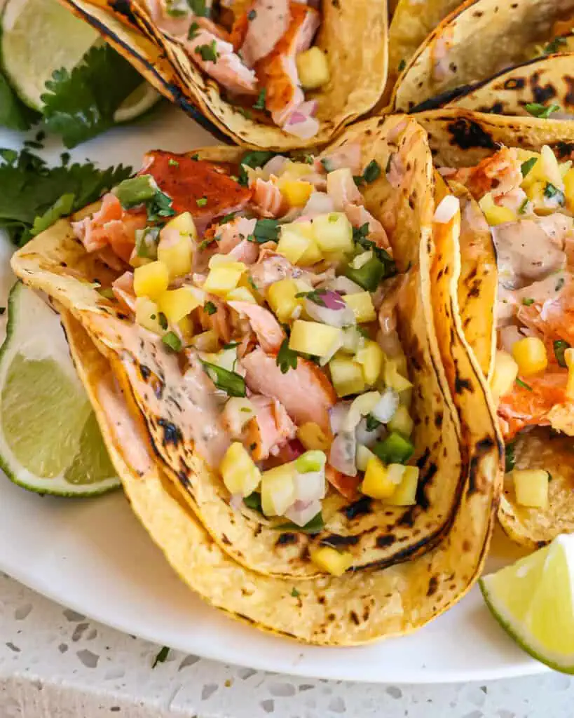 Easy Salmon Tacos made with pan-seared salmon served on corn tortillas with the tastes of mango salsa and chipotle ranch.