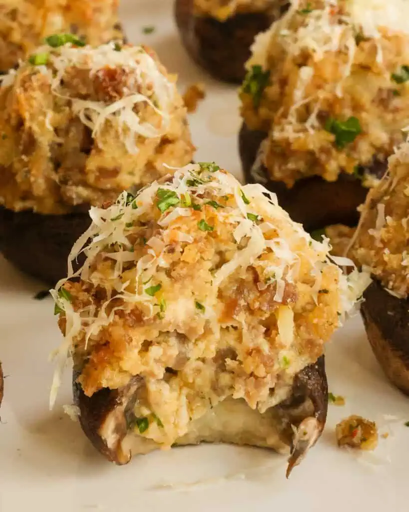 Sausage stuffed mushrooms with a bite missing. 