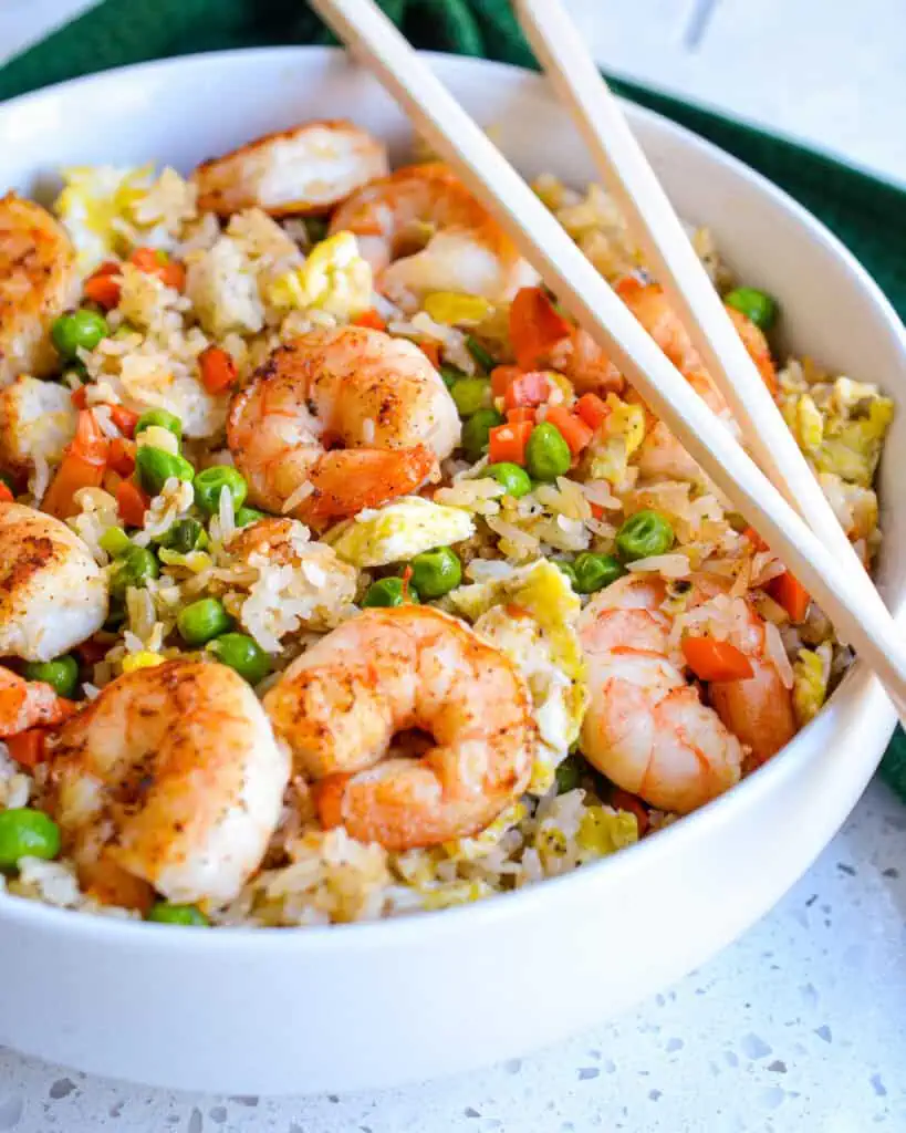 Tasty, tender shrimp are nestled in perfectly seasoned fried rice with carrots, peas, onions, and fluffy eggs.