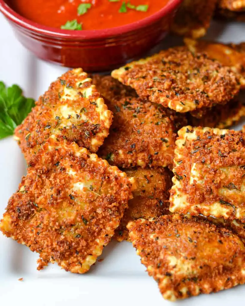Toasted ravioli on a serving platterwith a smal bowl of marinara. 