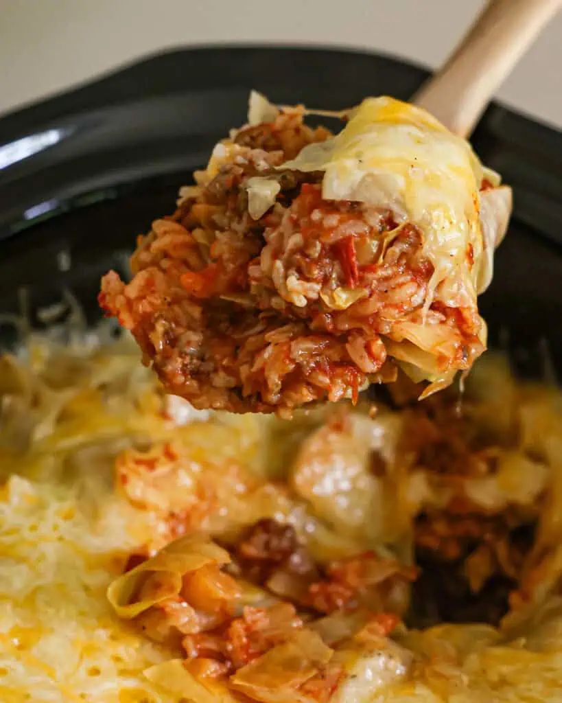 A large spoon filled with crock pot cabbage roll casserole.